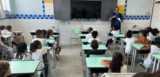Numa sala de aula, em primeiro plano, sentados e de costas, estudantes do Centro Escolar Macabu,...