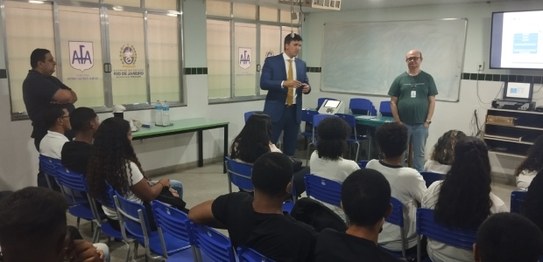 Numa sala de aula, em primeiro plano, sentados e de costas, estudantes do CIEP 364 Nelson Ramos,...