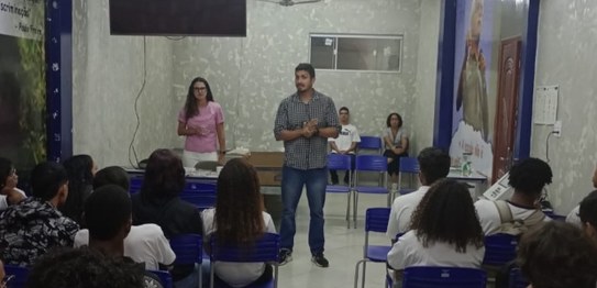 Numa sala, sentados, estudantes assistem à palestra da juíza eleitoral Renata Palheiro e do chef...