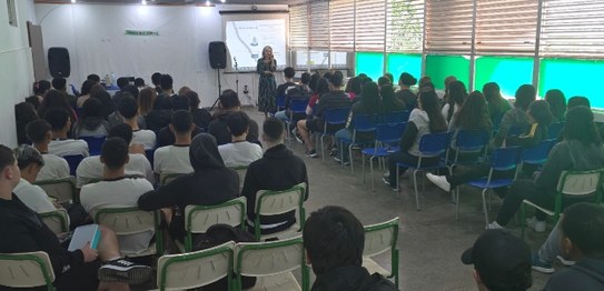 Duas mulheres estão em pé conduzindo uma palestra para um grupo de estudantes em uma sala de aula.