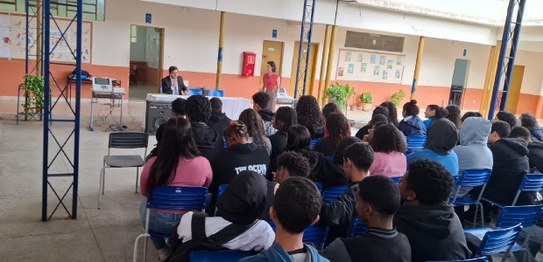Duas mulheres estão em pé conduzindo uma palestra para um grupo de estudantes em uma sala de aula.