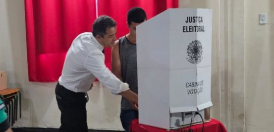 O juiz Luiz Olímpio Mangabeira Cardoso ajuda um estudante de Sapucaia a utilizar a urna eletrônica