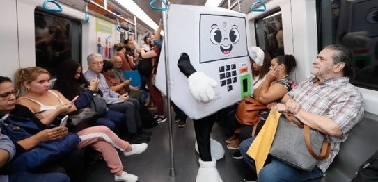 Na estação de metrô, o presidente do TRE-RJ Claudio de Mello Tavares aponta sorrindo para a plac...