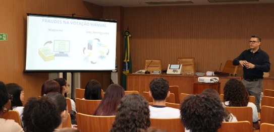 Um grupo de pessoas de diversas idades posa no plenário do TRE-RJ.