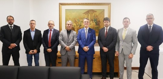 Grupo de oito homens posicionados lado a lado, em pé e alinhados horizontalmente no centro da im...