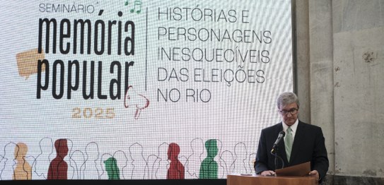 A imagem mostra um grande painel com o nome do seminário em letras destacadas, usando uma mistur...