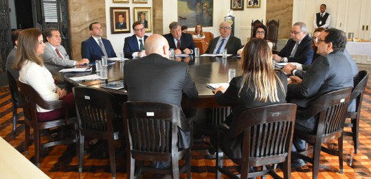 Foto tirada durante a reunião do Fojurj com 13 magistradas(os) sentadas(os) ao redor de uma gran...