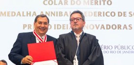 Presidente Peterson Simão posa segurando um certificado, com a medalha ao peito, usando terno e ...