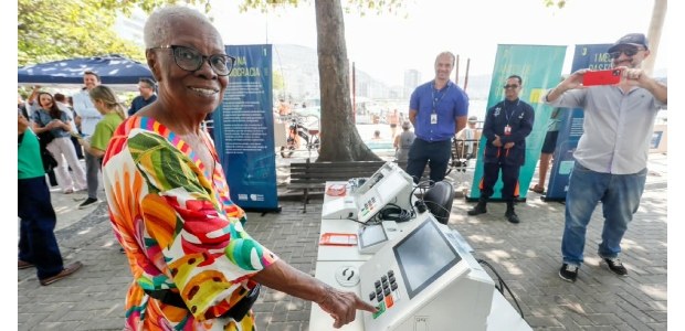 Com sorriso largo, Neuza Silva está votando na urna eletrônica instalada no calçadão da Praia de...