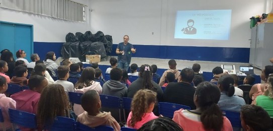 Servidora da Justiça Eleitoral realiza palestra sobre cidadania para estudantes, que estão senta...