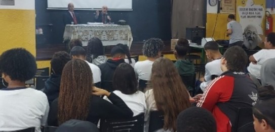 Descrição da imagem: À direita, o juiz Otávio Mauro Nobre, de camisa azul, projeta uma apresenta...
