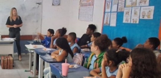 Descrição da imagem: À direita, o juiz Otávio Mauro Nobre, de camisa azul, projeta uma apresenta...