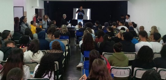 Descrição da imagem: À direita, o juiz Otávio Mauro Nobre, de camisa azul, projeta uma apresenta...