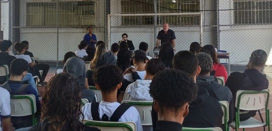Descrição da imagem: À direita, o juiz Otávio Mauro Nobre, de camisa azul, projeta uma apresenta...
