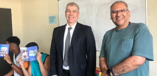 Descrição da imagem: Cinco alunos(as), três meninas e dois meninos, estão em pé e fazem fila par...