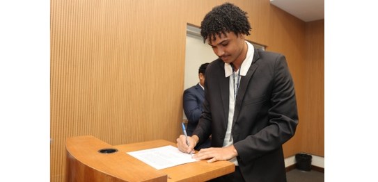 O novo servidor, Robson de Paula Mendes, está com uma caneta nas mãos enquanto assina seu termo ...