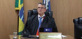 Foto do presidente do TRE-RJ, desembaragador Claudio de Mello Tavares, sentado à mesa, sobre o q...
