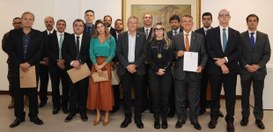 Quase 20 autoridades estão de pé, uma ao lado da outra, com vestimenta formal posando para a foto