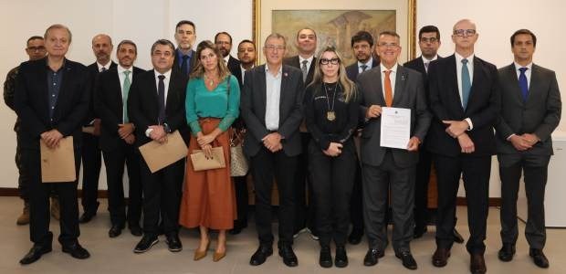 Quase 20 autoridades estão de pé, uma ao lado da outra, com vestimenta formal posando para a foto