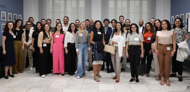 As(os) 28 novas(os) servidoras(es) estão de pé, posando para a foto na antessala do auditório. A...