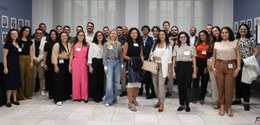 As(os) 28 novas(os) servidoras(es) estão de pé, posando para a foto na antessala do auditório. A...
