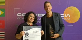 A servidora Claudeci Oliveira segura o certificado de 2º lugar na premiação ao lado do servidor ...