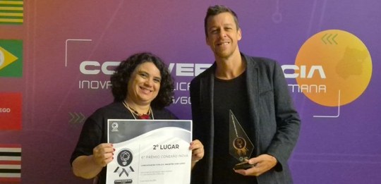 A servidora Claudeci Oliveira segura o certificado de 2º lugar na premiação ao lado do servidor ...