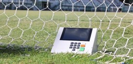 Uma urna eletrônica posicionada no gramado do Estádio Manoel Schwartz ou Estádio das Laranjeiras...