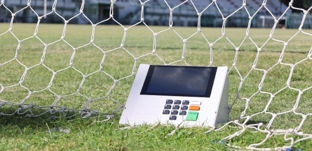 Uma urna eletrônica posicionada no gramado do Estádio Manoel Schwartz ou Estádio das Laranjeiras...