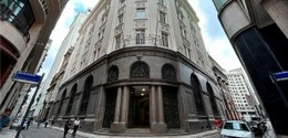 A imagem mostra uma vista de rua em uma área urbana, com um prédio distintivo na esquina. O edif...