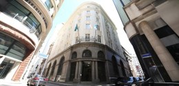 A imagem mostra um edifício histórico de esquina, com uma fachada imponente e detalhes arquitetô...