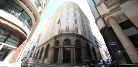 A imagem mostra um edifício histórico de esquina, com uma fachada imponente e detalhes arquitetô...