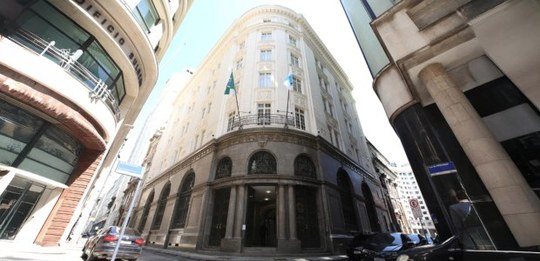 A imagem mostra um edifício histórico de esquina, com uma fachada imponente e detalhes arquitetô...