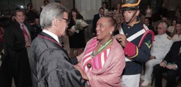 O presidente do Tribunal, de toga, cumprimenta a ministra Vera Lúcia, de roupa rosa. Um militar,...