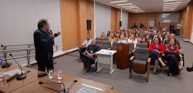 TRE-RJ: Liderança e IA são temas debatidos na abertura do 6º Desenvolve JE pessoas estão sentadas em cadeiras de madeira, voltadas para a frente da sala, onde há uma mesa....