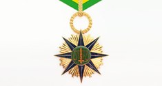 Ao centro de um fundo branco, uma medalha em ouro amarelo; sobreposta a esta medalha, uma estrel...