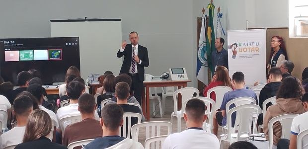 TRE-RJ Projeto #PartiuVotar leva palestras para escola na Região Serrana O juiz Rubens Soares Viana Junior, um homem branco, de terno preto e camisa branca, gesticula en...