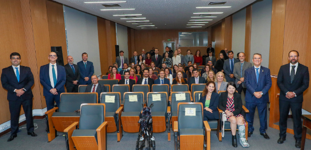 Grupo de aproximadamente 50 juízas e juízes no auditório do Palácio da Democracia. Estão vestido...