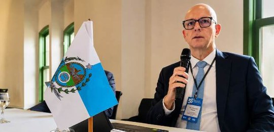 Em primeiro plano o desembargador Fernando Chagas, fala ao microfone, sentado à mesa. À sua esqu...