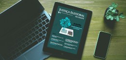 No centro da imagem um iPad com a capa da revista Justiça Eleitoral em Debate, ao lado de um not...