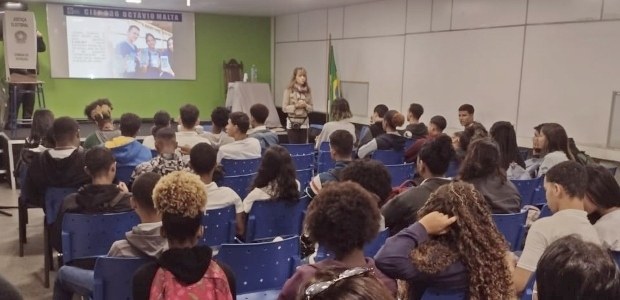 TRE Vai à Escola faz palestras para estudantes de Ensino Médio Foto da palestra, onde temos alunos em uma sala de aula e a juíza ao fundo